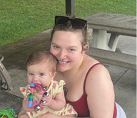 Kenwood Nursing and Rehab staff member, Mariah Bowling, pictured with young child in her arms, sitting in the park
