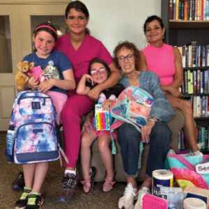 Kenwood Nursing and Rehab employee pictured with two other women and two little girls celebrating their backpack and school supply giveaway.